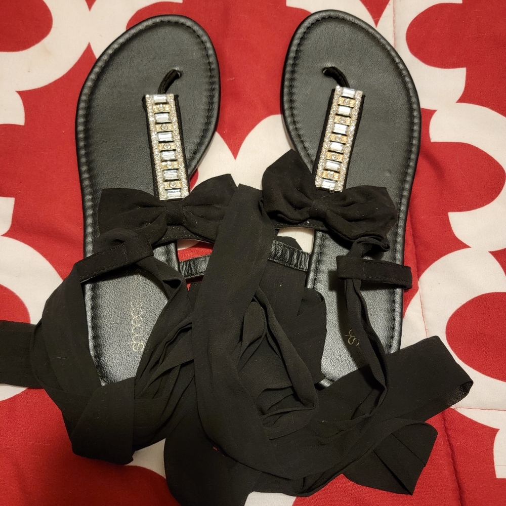 Flat sandel with bow and crystal accent. Laces up leg.